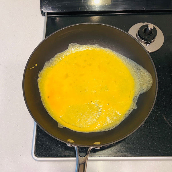 adding the egg mixture to a large frying pan