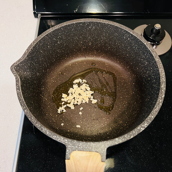 adding garlic to a frying pan