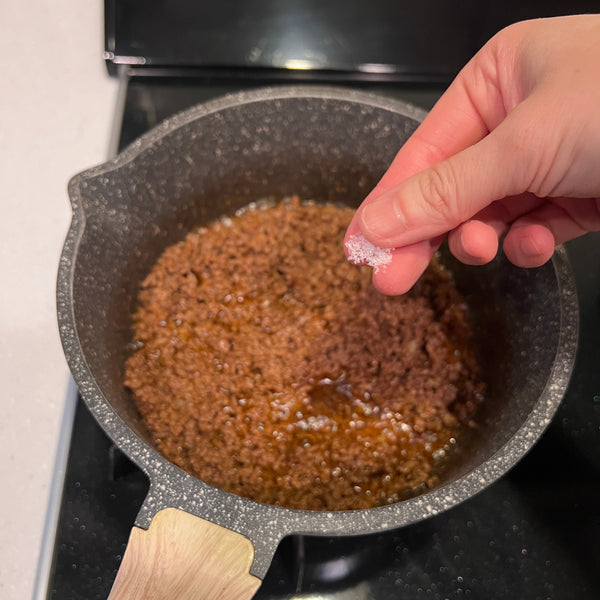 seasoning the taco meat with salt